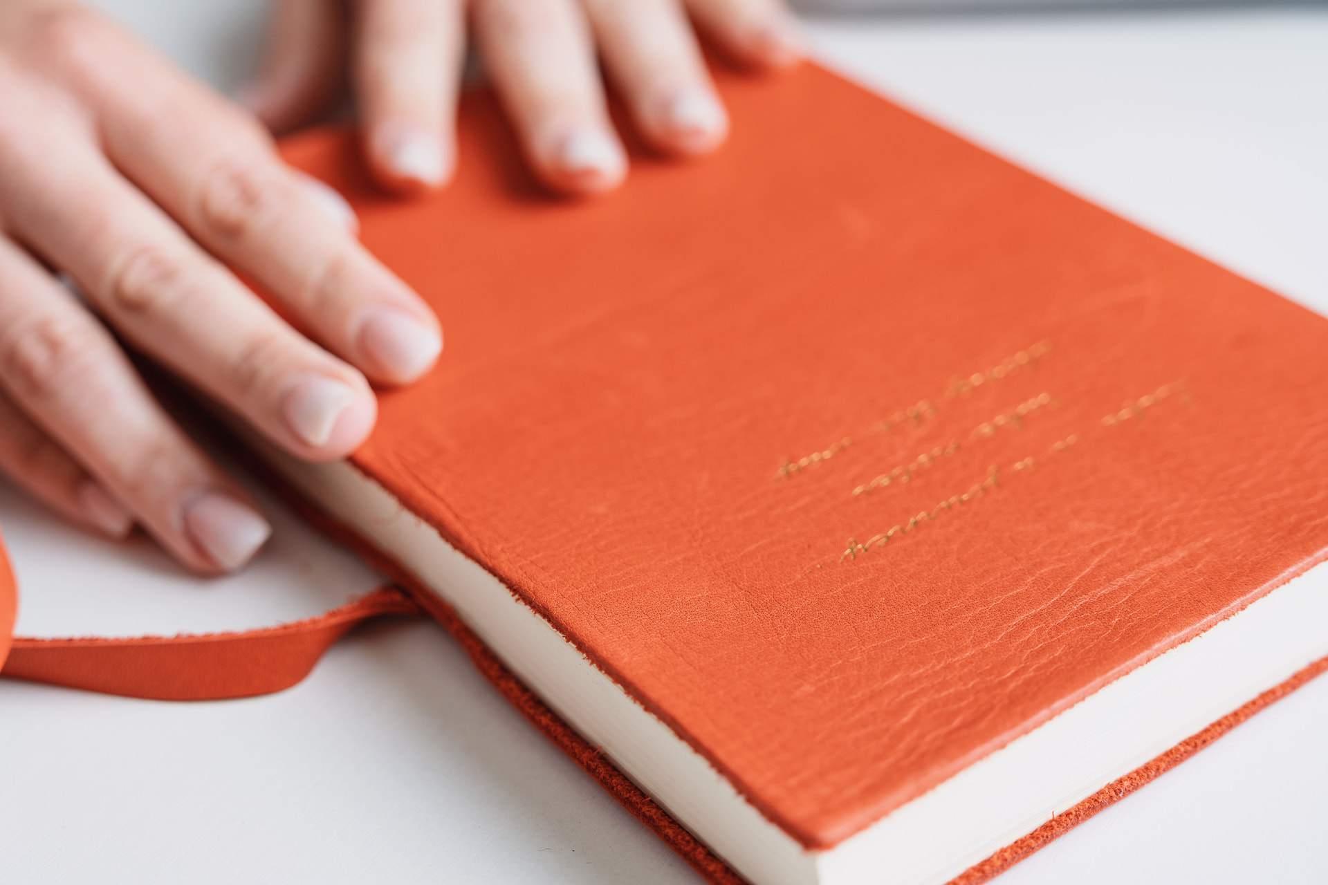 Hands resting on an orange leather journal